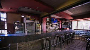 Un espace bar avec un comptoir, des tabourets et un réfrigérateur.