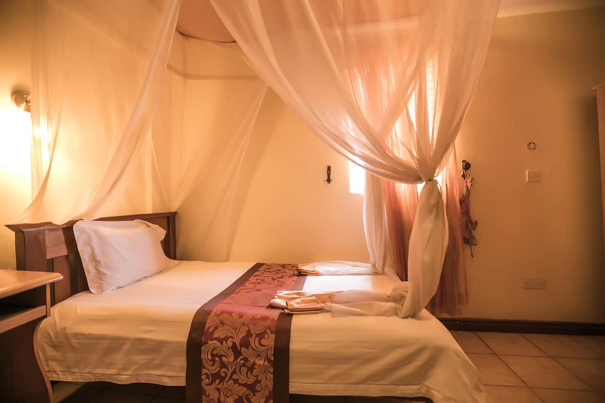 Une chambre d’hôtel avec un lit, une table de chevet et une fenêtre avec des rideaux.