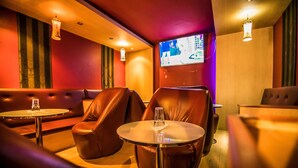 Un espace détente moderne avec des fauteuils en cuir, de petites tables rondes et un éclairage d’ambiance.