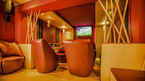 Un espace détente moderne avec des fauteuils en cuir, un écran de télévision et un plancher en bois.