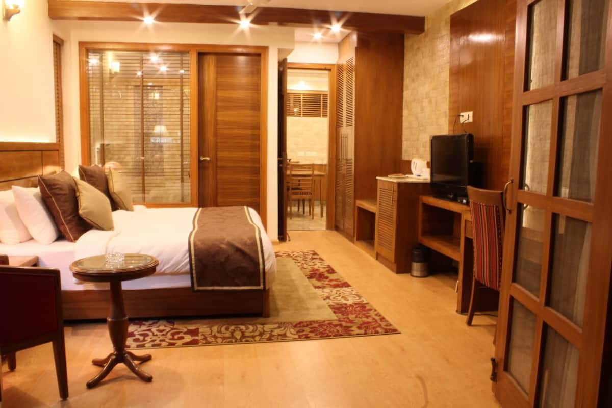 A hotel room with a bed, a small table, a TV, and a wardrobe.