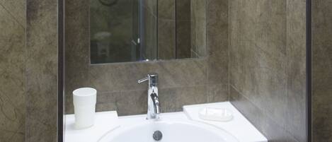 A modern bathroom with a large mirror, a sink, and a shower.