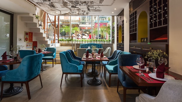 Een restaurant met blauwe stoelen, een houten tafel en uitzicht op de straat.