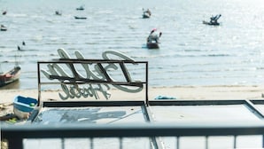 A metal sign with the name "JULIA'S" on a beach with boats in the background. - Betta Hostel (Chonburi)