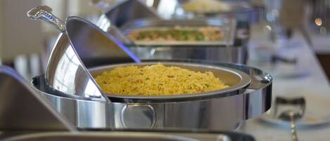 A buffet with various dishes, including a pot of rice and other food items.