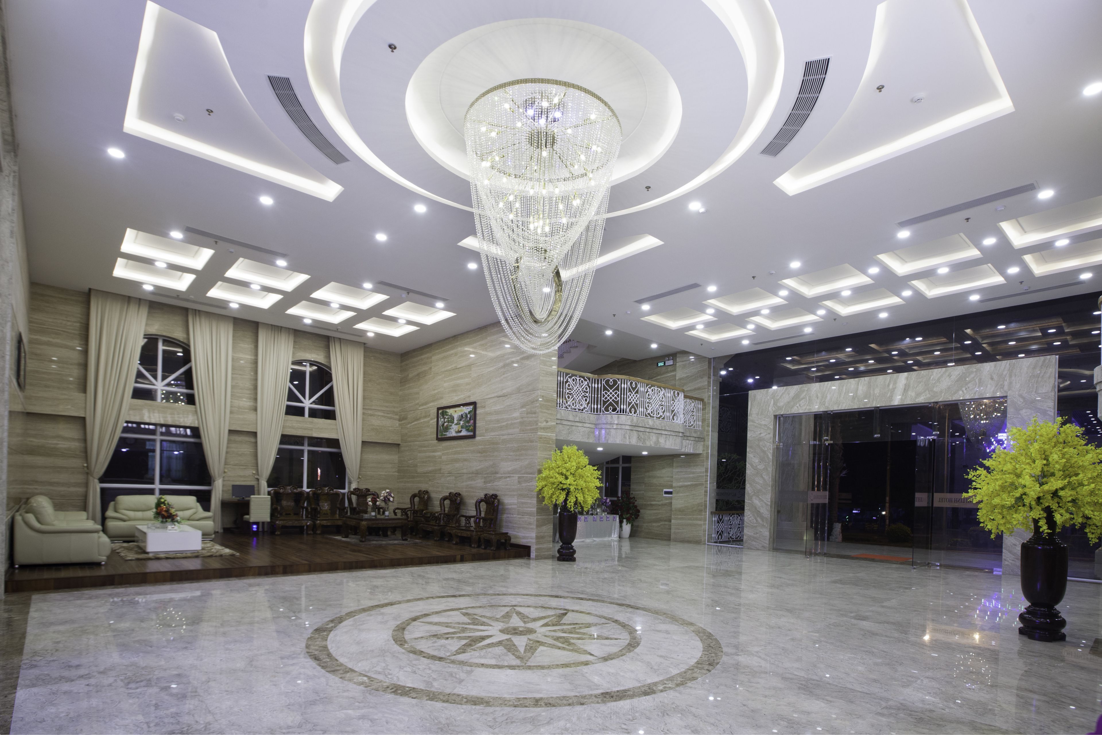 A spacious lobby with a large chandelier, a reception desk, and a seating area with sofas and chairs.