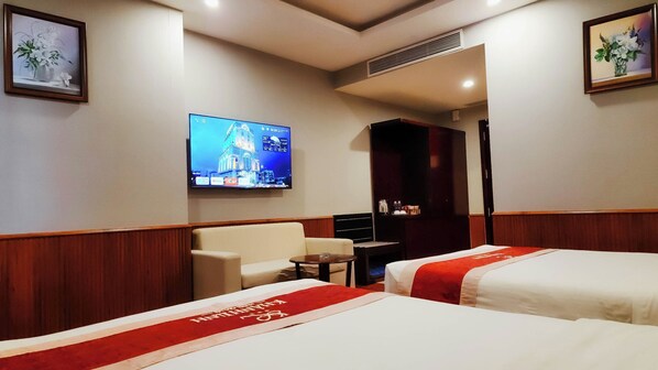 A hotel room with two beds, a television mounted on the wall, a small table, and a chair. - Khánh Linh Hotel (Pleiku)
