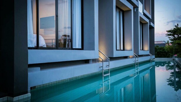 Un hôtel moderne doté d’une piscine, de grandes fenêtres et d’un design épuré et contemporain.