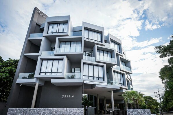 Un hotel moderno de varios pisos con un diseño arquitectónico singular, que cuenta con balcones y amplias ventanas.