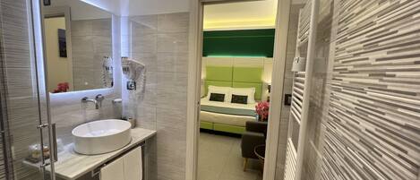 Un baño moderno con cabina de ducha de vidrio, un lavabo blanco y un espejo.