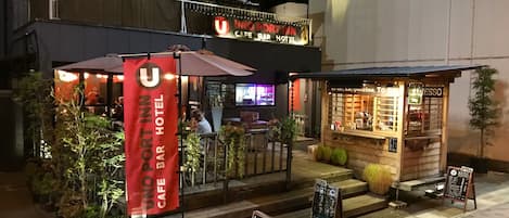 Un bar y hotel llamado "UNO PORT INN" con mesas al aire libre y un cartel de menú.
