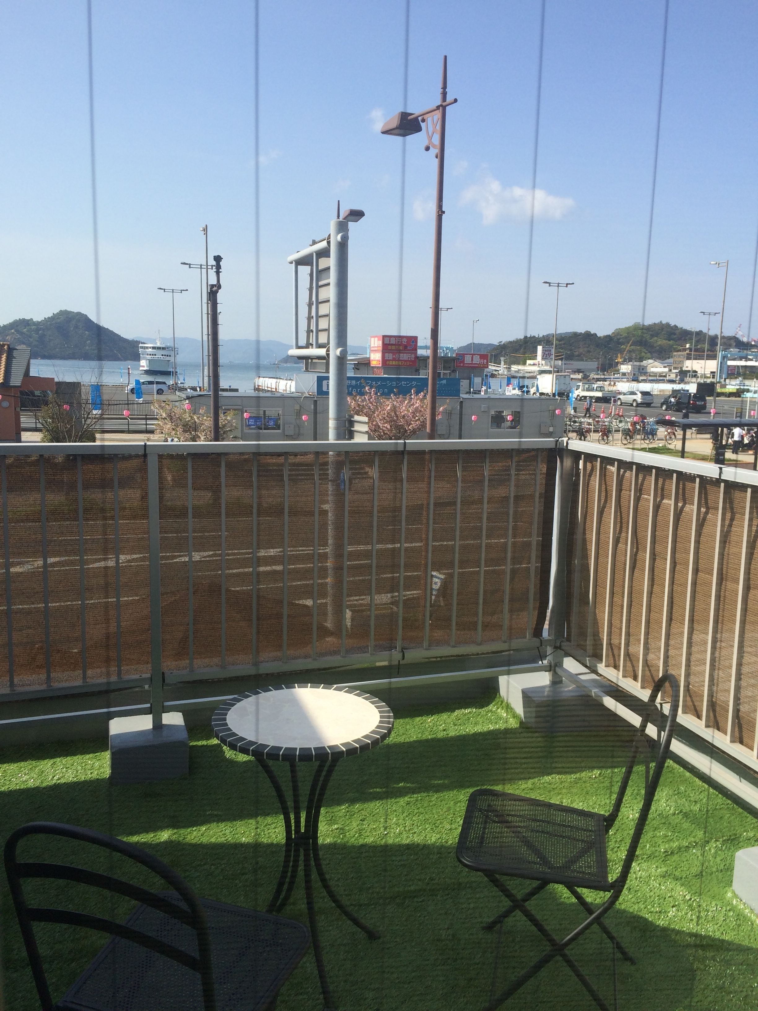 A balcony with artificial grass, a table, and two chairs.