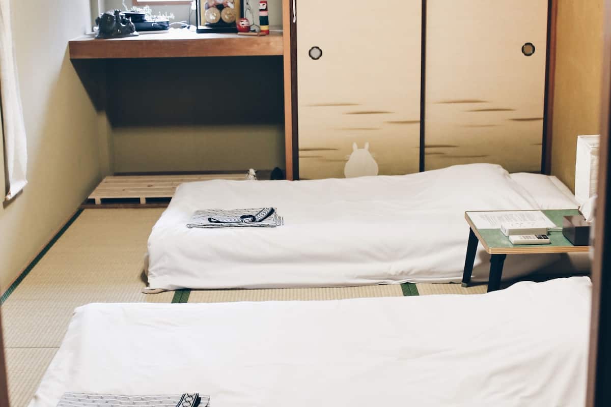 A room with two beds, a small desk, and a wardrobe.