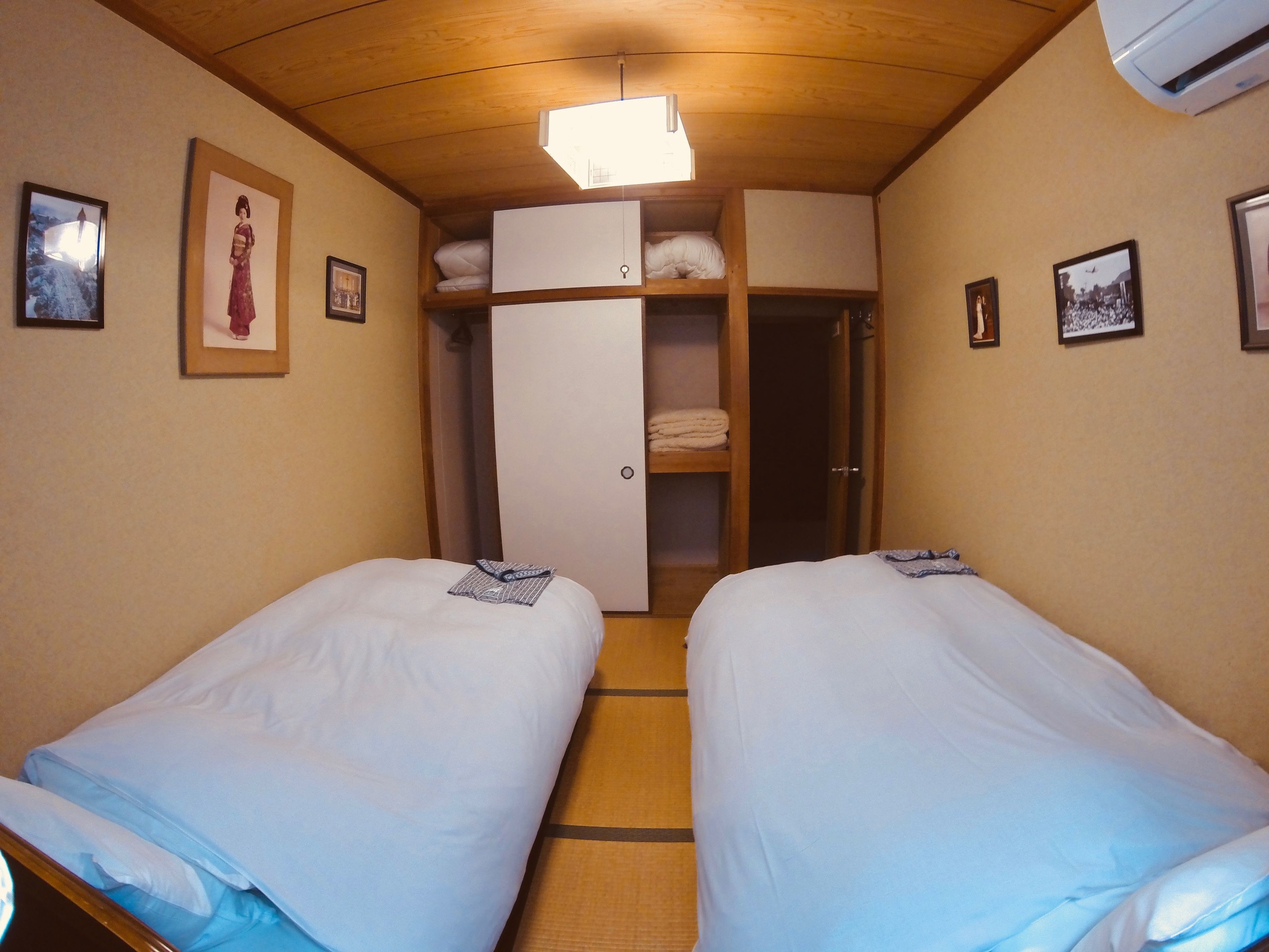 Una habitación con dos camas individuales, un armario y un ventilador de techo.