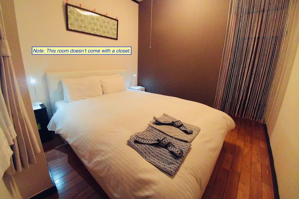 A neatly made bed with a patterned blanket and a pair of sandals on it.