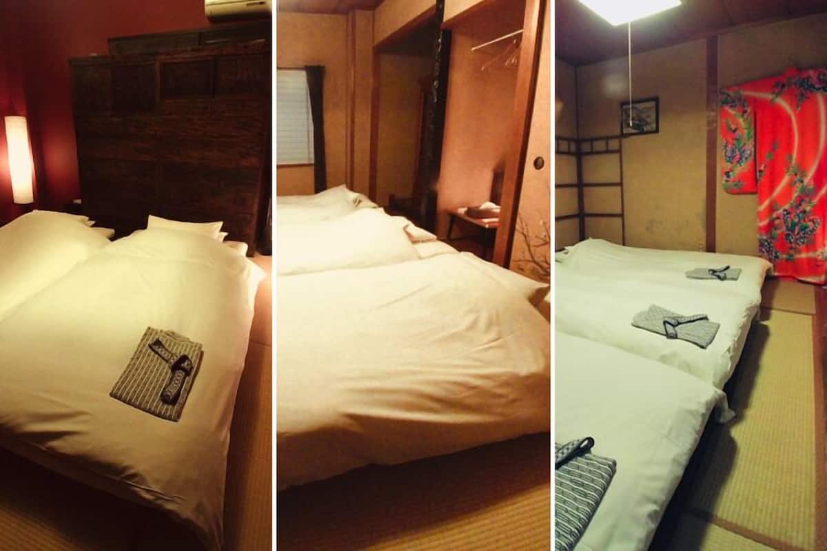 A hotel room with a wooden headboard, a bed with white linens, a bedside table, and a red curtain.