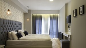 A modern bedroom with a tufted headboard, a large bed, a desk, and a television. - Venis Boutique Residence (Bucharest)