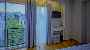 A hotel room with a large window, a desk with a TV, and a small plant. - Venis Boutique Residence (Bucharest)