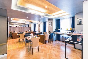 A modern dining area with wooden flooring, multiple seating arrangements, and a buffet station. - Venis Boutique Residence (Bucharest)