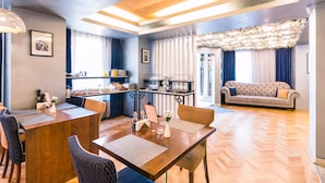 A modern living room with a sofa, dining table, and kitchen area. - Venis Boutique Residence (Bucharest)