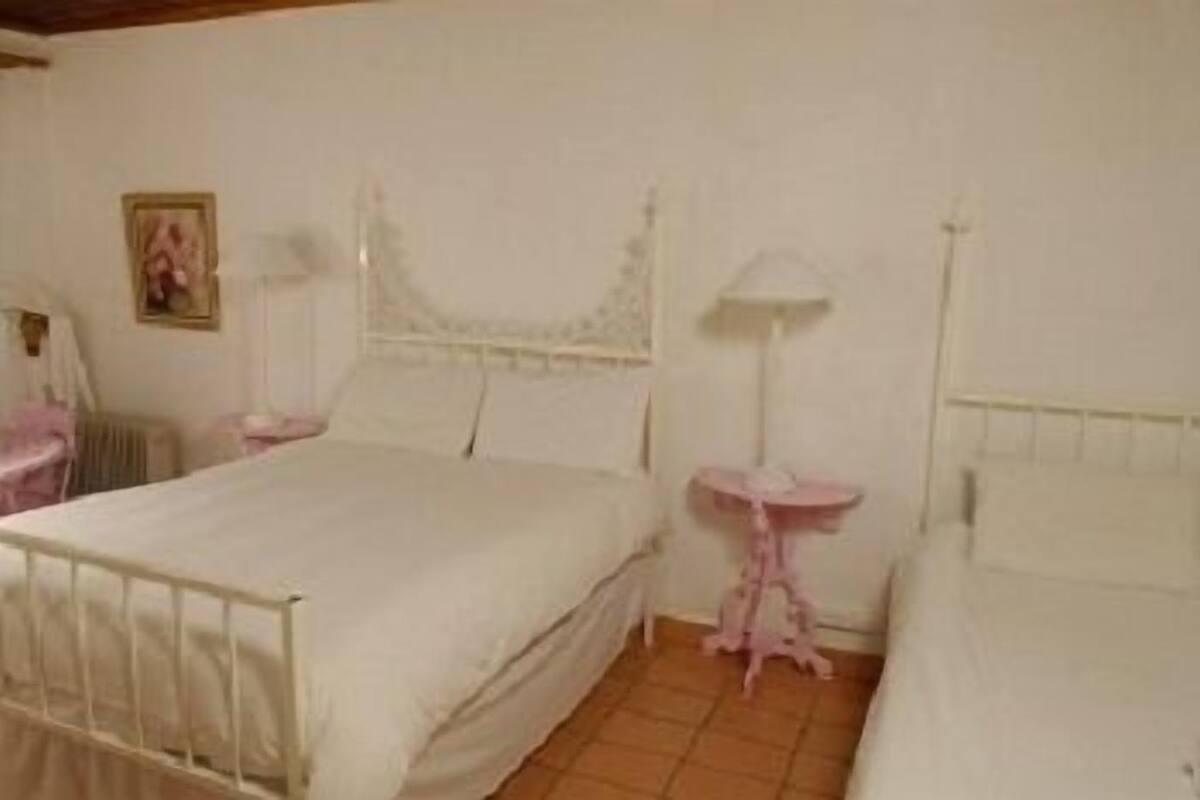 Un dormitorio con cama, una mesita de noche, una lámpara y un estante en la pared.