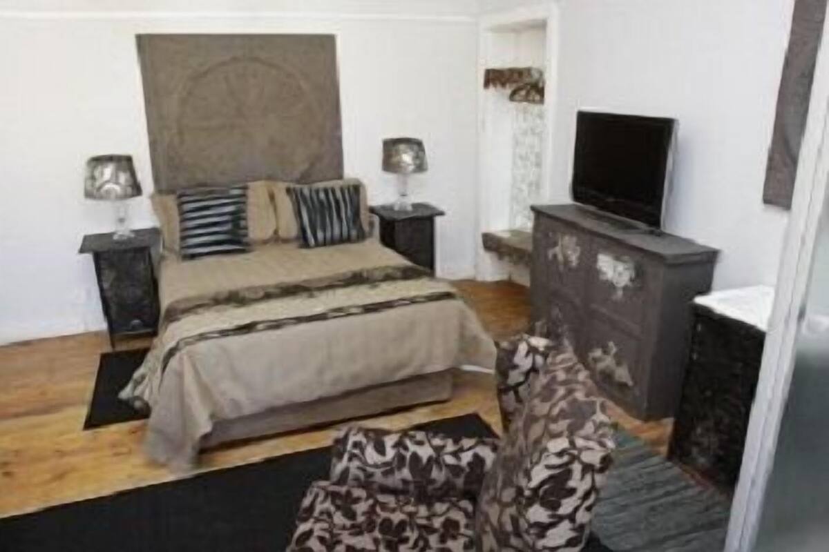 Un dormitorio con cama, dos mesitas de noche, televisión y cómoda.