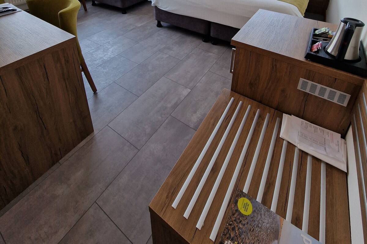 A hotel room with two single beds, a sofa, a wooden desk, and a chair.