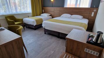 A hotel room with two single beds, a sofa, a wooden desk, and a chair.
