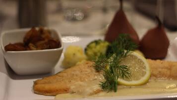 A plate with a fish fillet, lemon, dill, and a side of potatoes.
