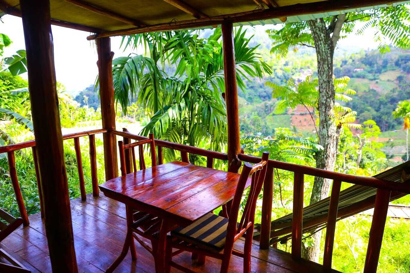 A wooden deck with a table and chairs, overlooking a lush green landscape.