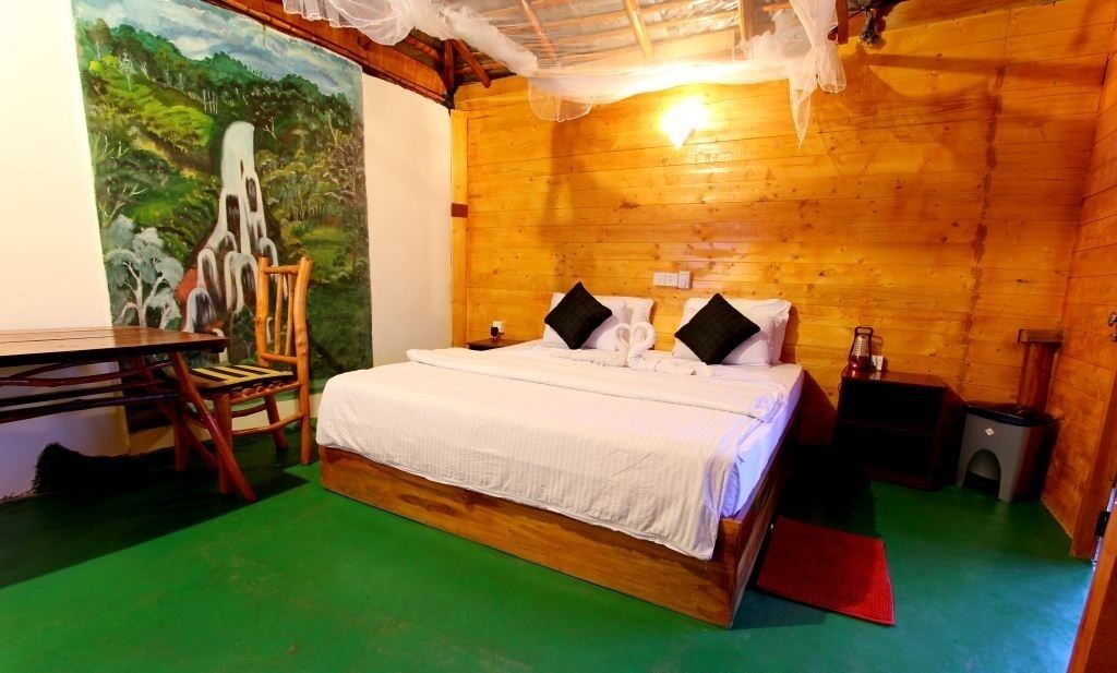 A wooden room with a bed, a chair, a table, and a mural on the wall.