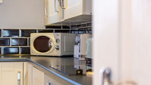 A kitchen with a microwave, toaster, and cabinets. - Church View Apartments (Weymouth)