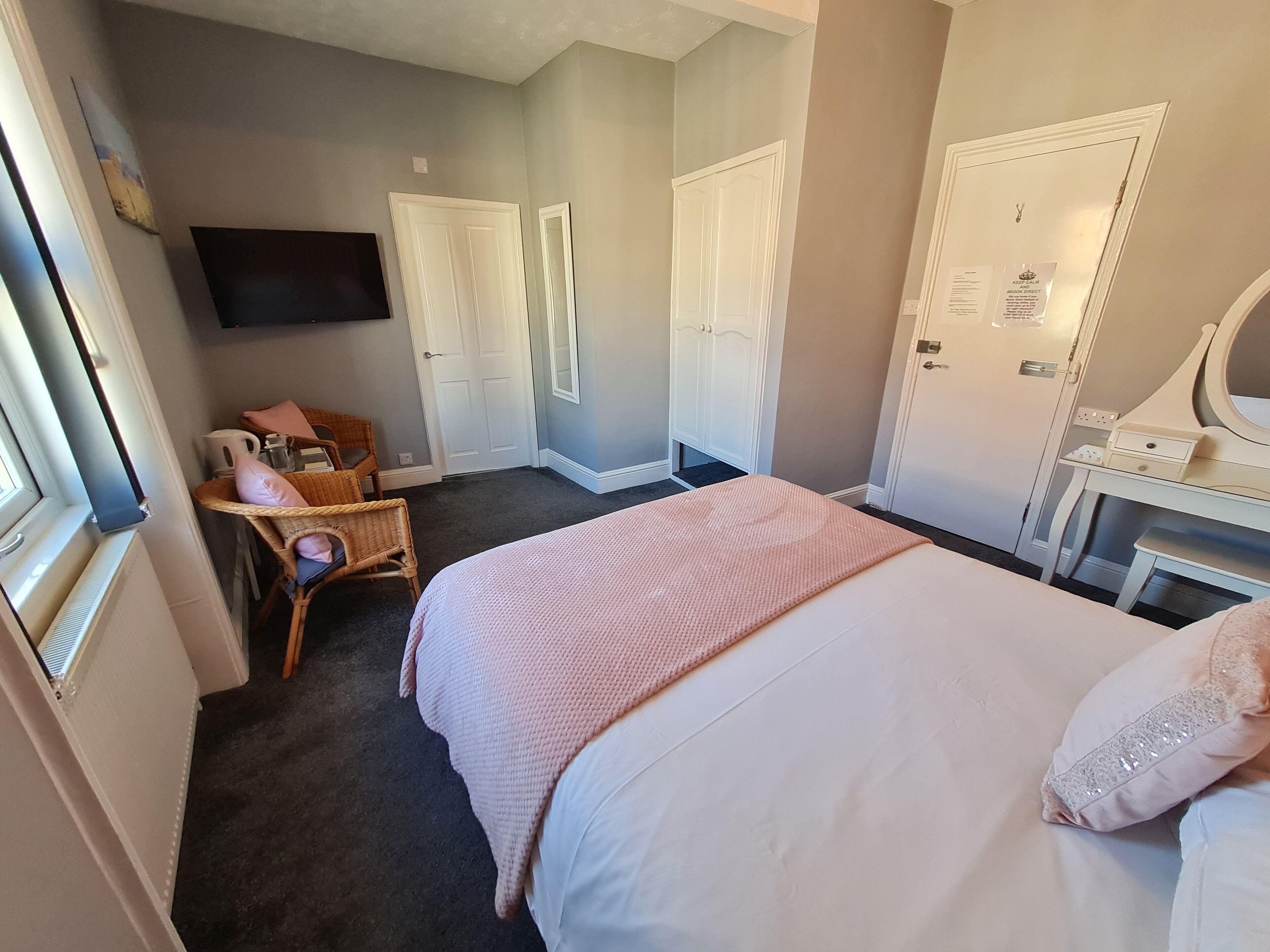 A bedroom with a bed, a dresser, a chair, a television, and two doors.