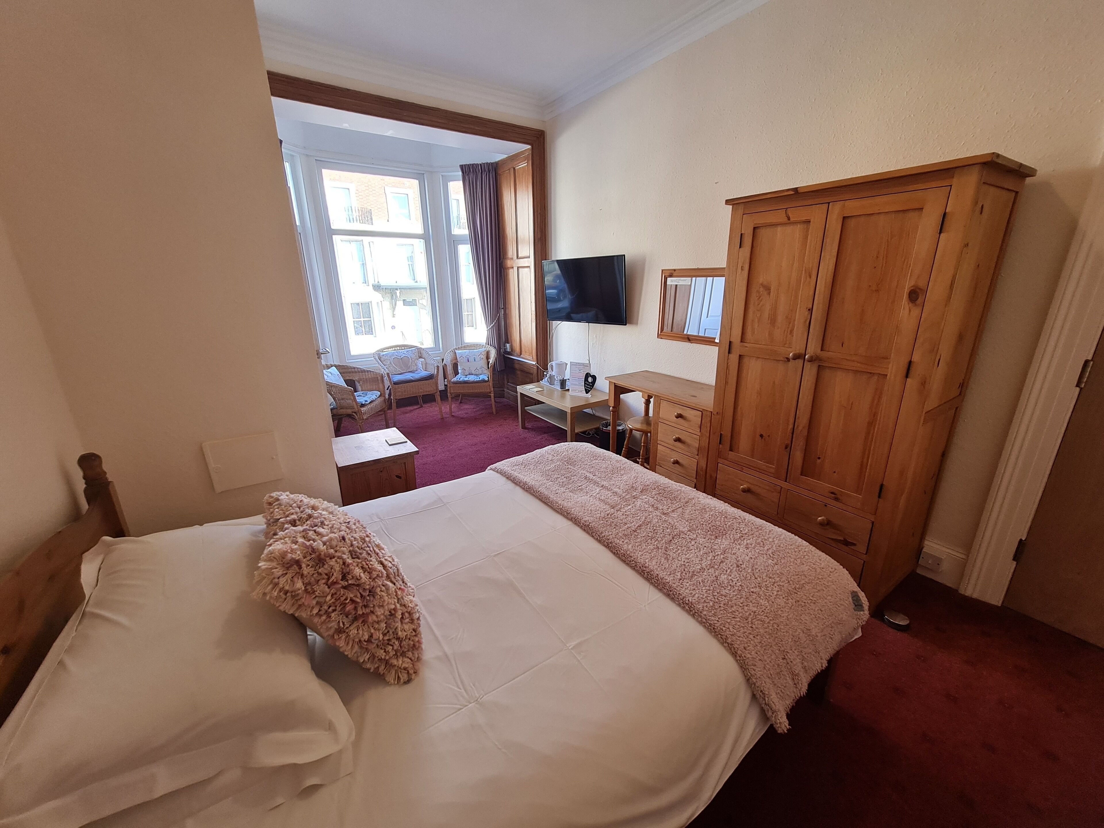A hotel room with a bed, a desk, a wardrobe, and a TV.