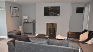 Una sala de estar con un sofá gris, una chimenea, un televisor y un mueble bajo.