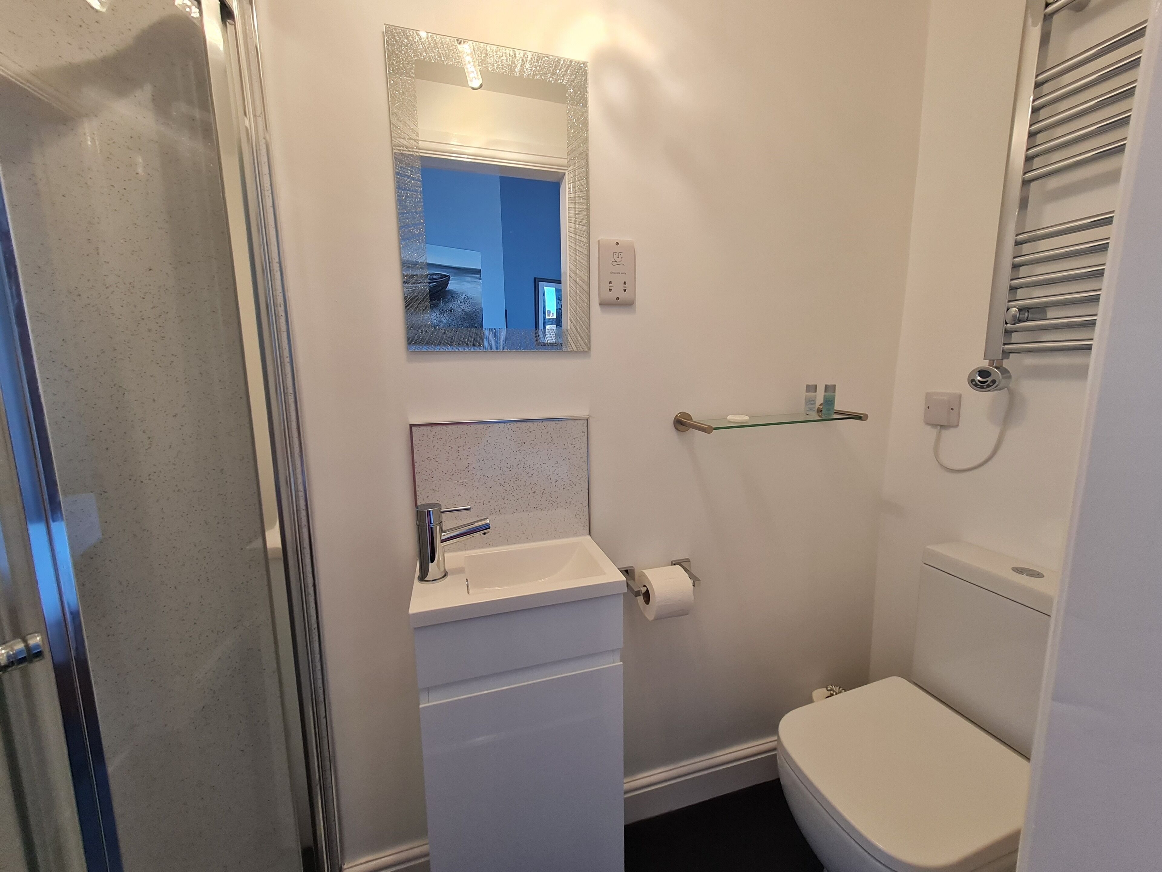 A compact bathroom with a toilet, sink, and glass shower enclosure.