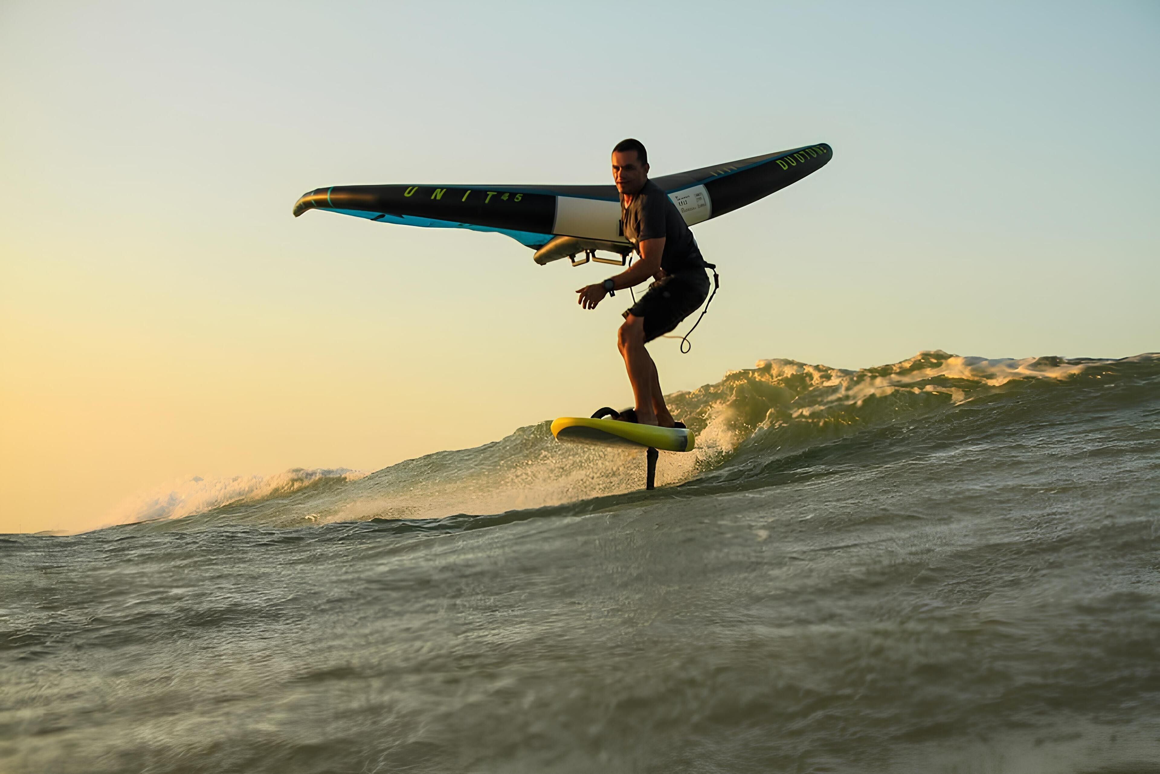 A person surfing on a wave with a surfboard that has "UNIT 45" written on it.
