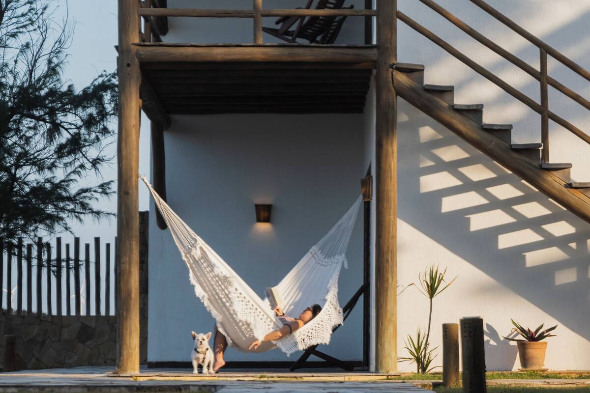 Un bâtiment avec un escalier en bois, un hamac et un chien.