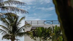 Un edificio moderno con techo plano, rodeado de exuberante vegetación y palmeras.