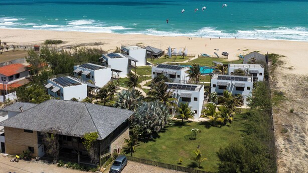Un resort costero con varias edificaciones, una playa y vista al océano.