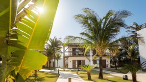 Un resort con un camino central, palmeras y un edificio con balcones.