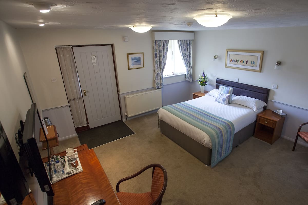 Ein Hotelzimmer mit Bett, Nachttisch, Stuhl, Schreibtisch und Fernseher.