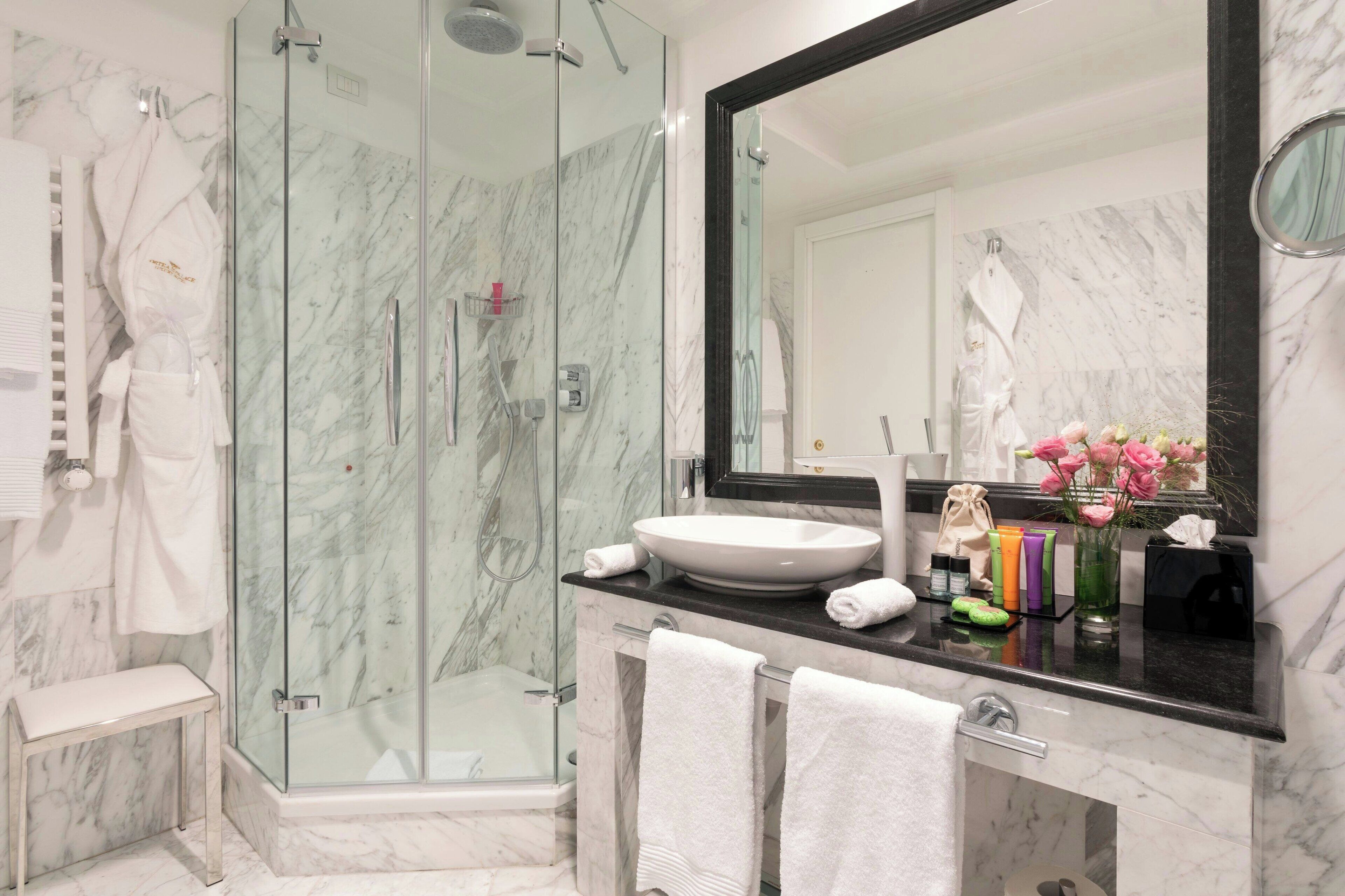 Une salle de bain moderne avec une douche à parois de verre, un grand miroir et un plan de toilette en marbre.