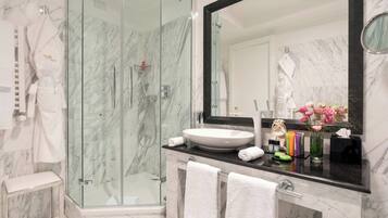 Une salle de bain moderne avec une douche à parois de verre, un grand miroir et un plan de toilette en marbre.