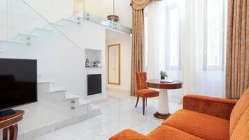 Un soggiorno moderno con una TV a schermo piatto, un divano, un tavolo da pranzo e una scala.