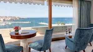 A balcony with a view of the sea and a cityscape, furnished with two chairs and a small table with a vase of flowers. - Ortea Palace Hotel, Sicily, Autograph Collection (Syracuse)