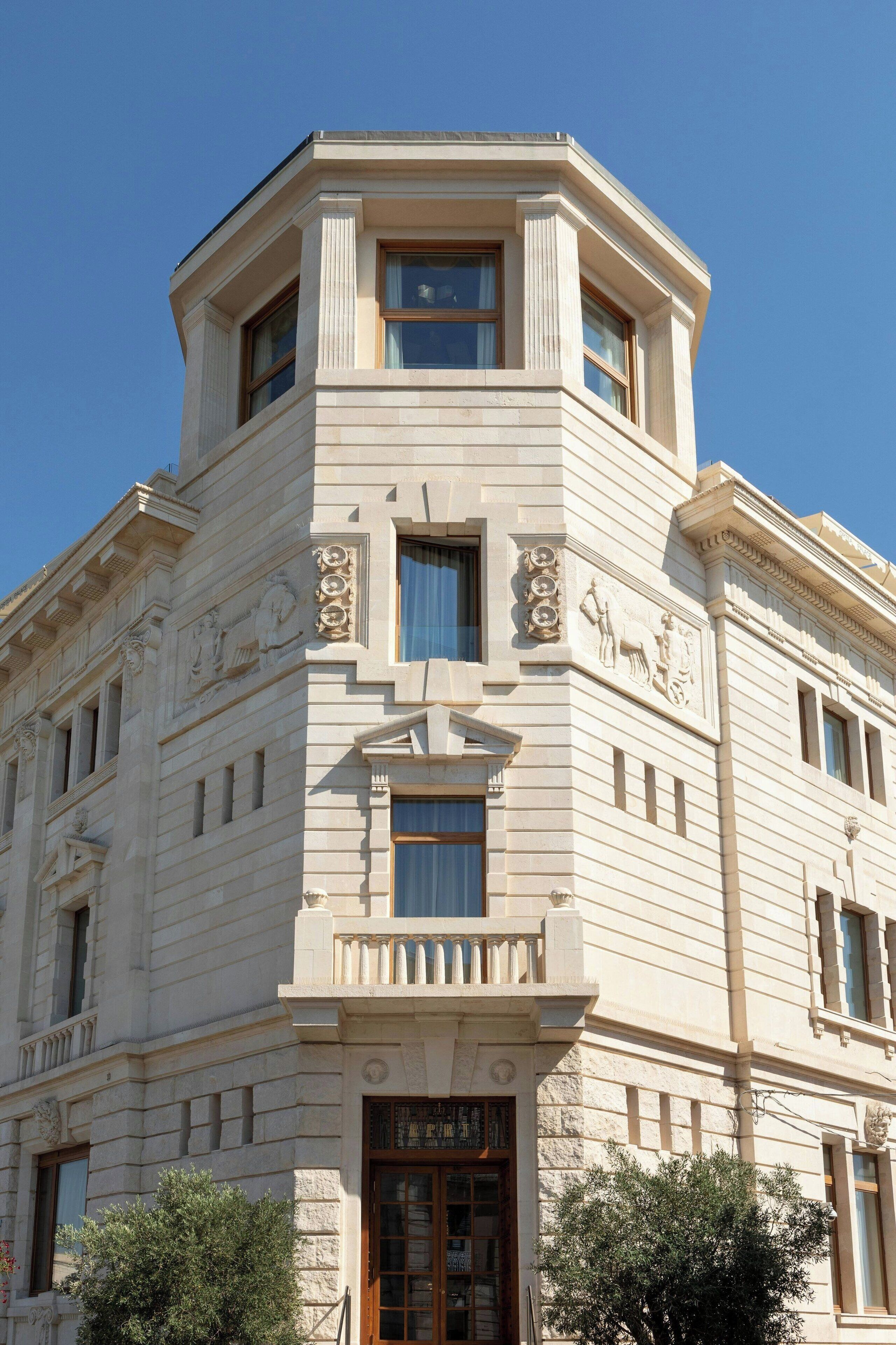 Ein Eckgebäude mit klassizistischen architektonischen Details, darunter Säulen undorative Verzierungen.