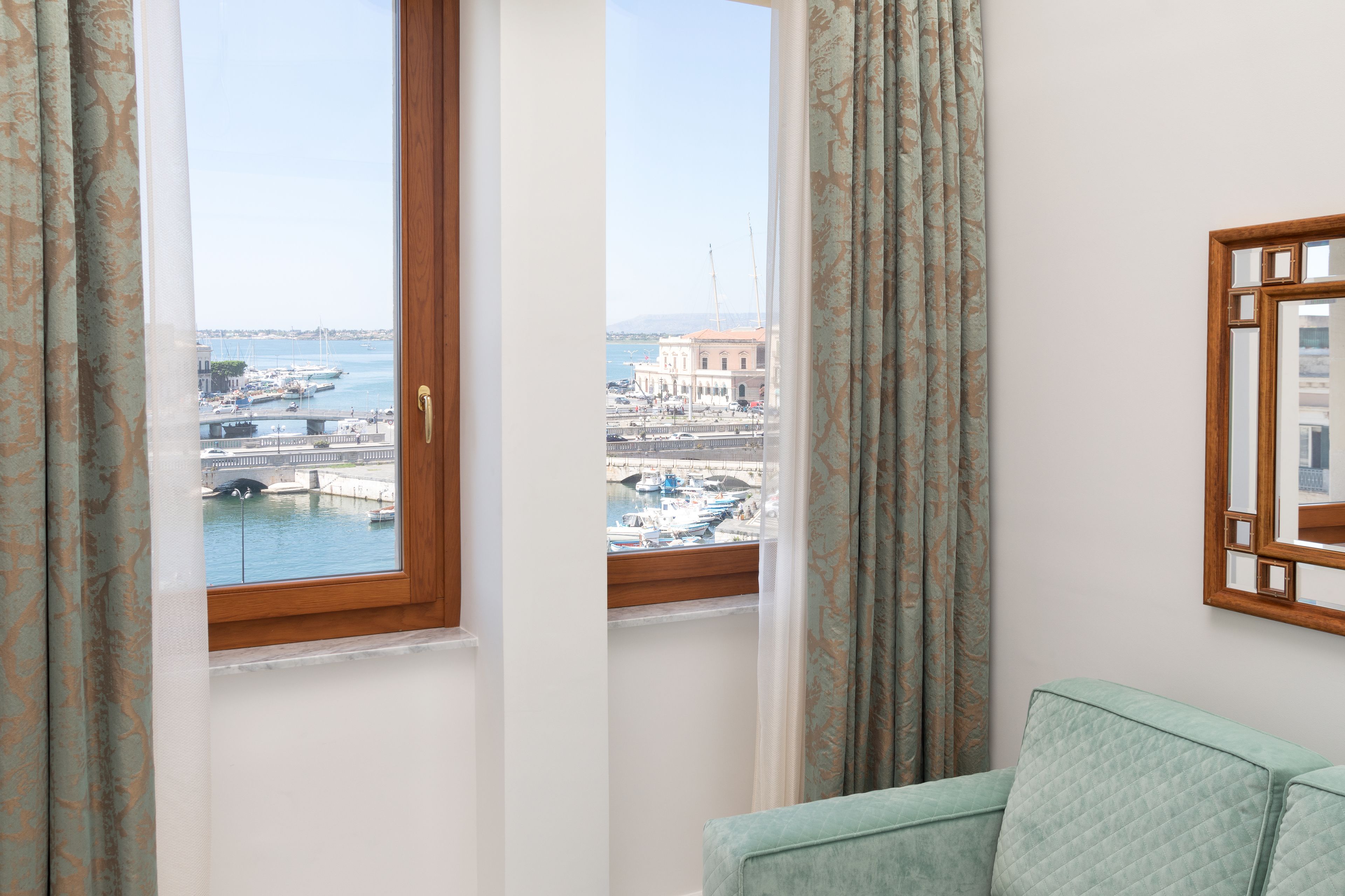 Une pièce avec vue sur un port de plaisance, un canapé et un miroir encadré en bois accroché au mur.