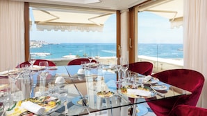 A dining table with multiple plates and wine glasses, set against a backdrop of a scenic ocean view. - Ortea Palace Hotel, Sicily, Autograph Collection (Syracuse)