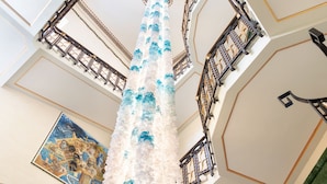 A grand atrium with a central column, ornate railings, and a large mural on the wall. - Ortea Palace Hotel, Sicily, Autograph Collection (Syracuse)